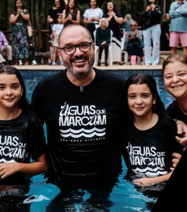 Pastor e batizandos na piscina com camisetas Águas que marcam