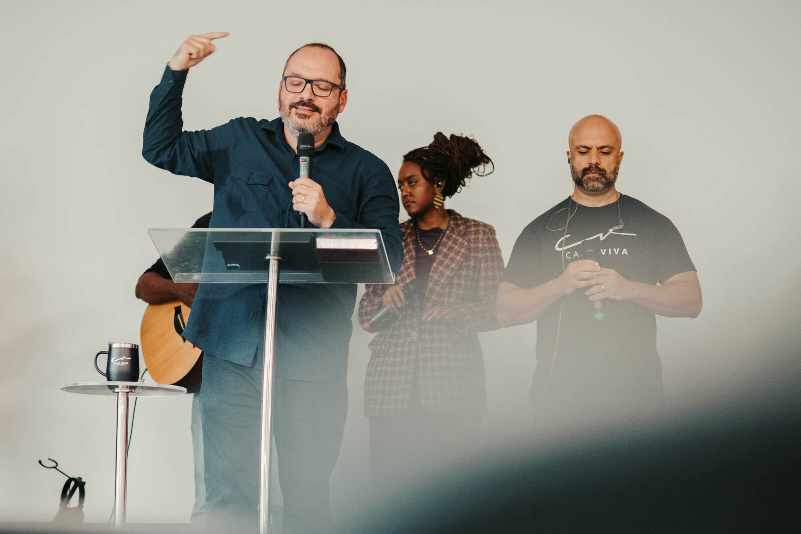 Pastor pregando ao lado da equipe de louvor