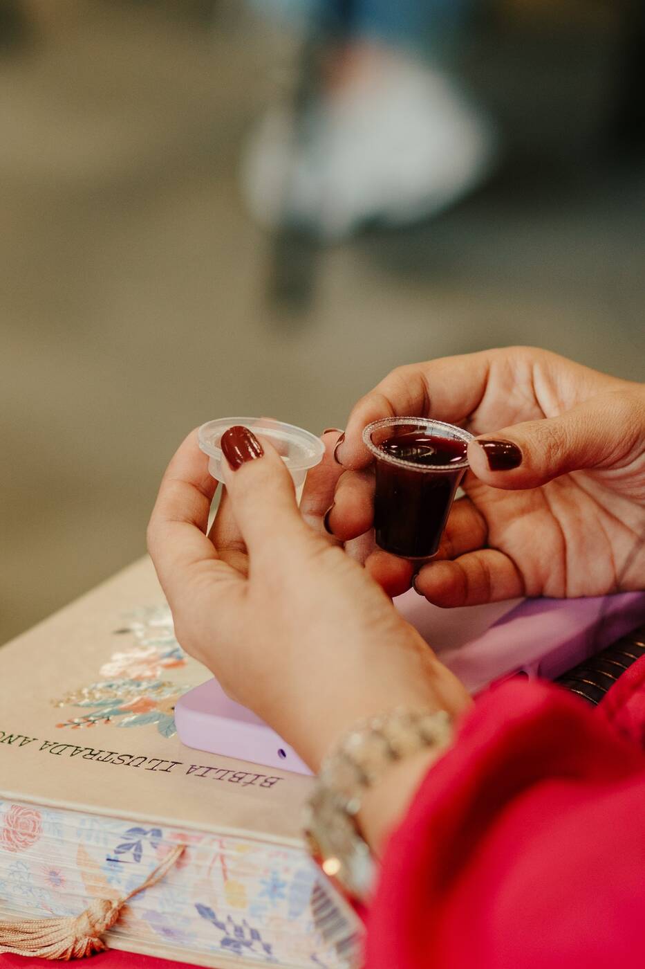 Mãos segurando os elementos da ceia sobre a Bíblia